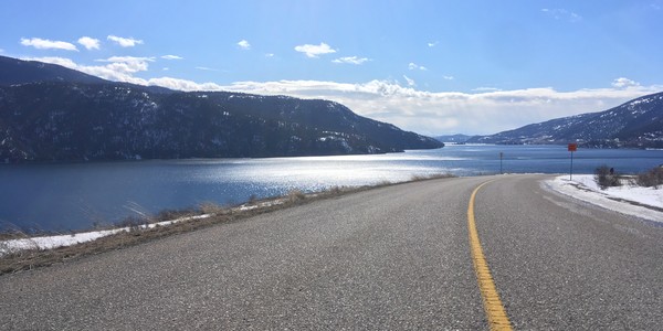 Country road with lake, mountains in background