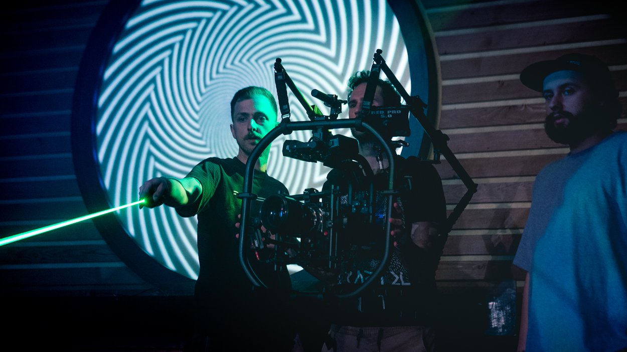 Gaffer Kyle Pigeau with a lazer pointer, checking the frame for rogue pieces of furniture. BTS by Tal Vardi.
