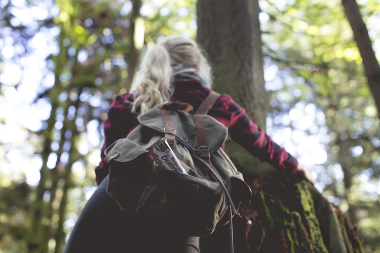Girl with Kinder Bueno climbing tree in forest